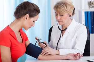 A female doctor checking the blood pressure of a woman.